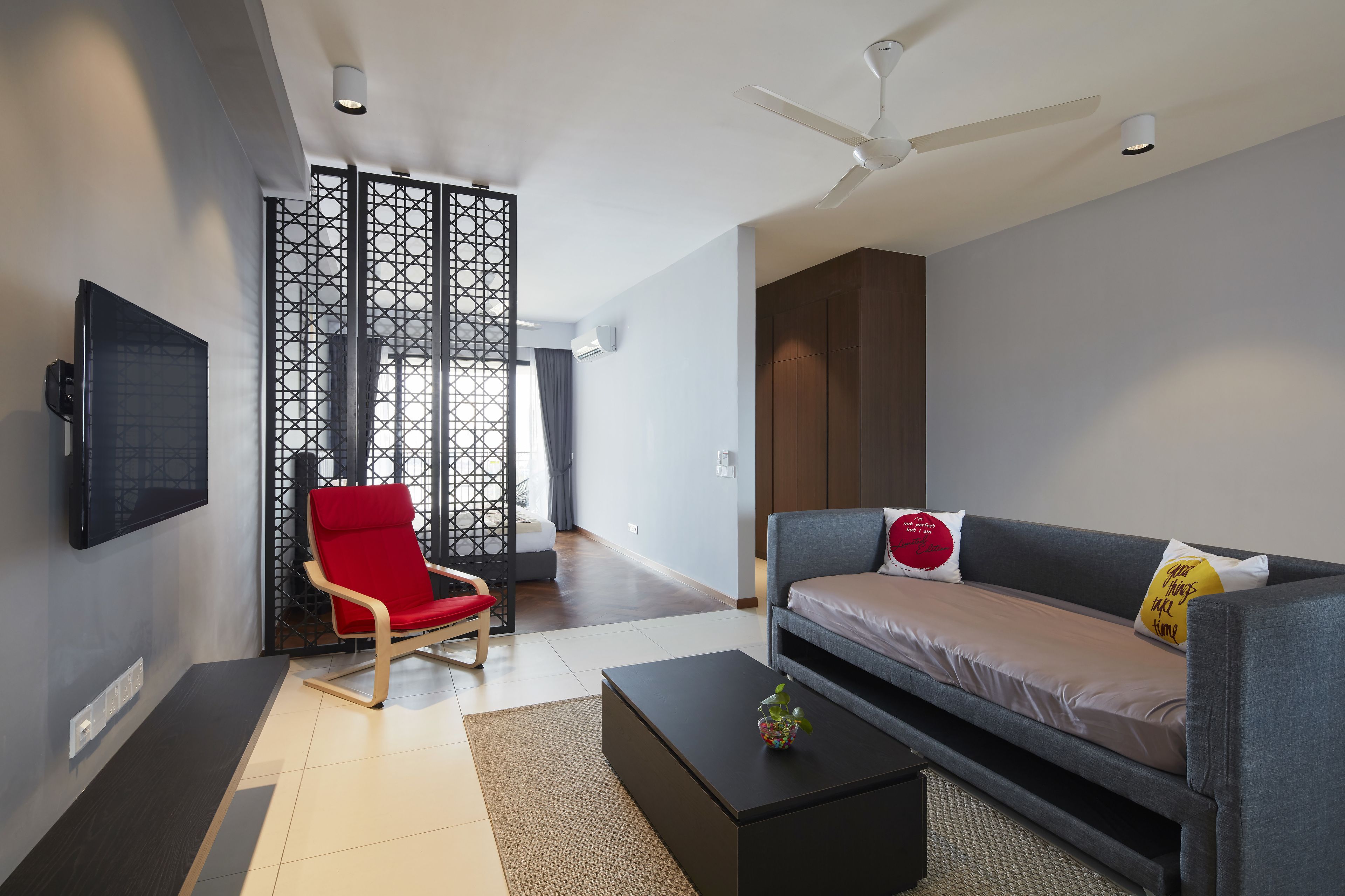 Una sala de estar moderna con un sofá, una silla roja y un televisor de pantalla plana.