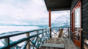 A wooden deck with a view of a snowy landscape and mountains. - Hotell Fjället (Björkliden)