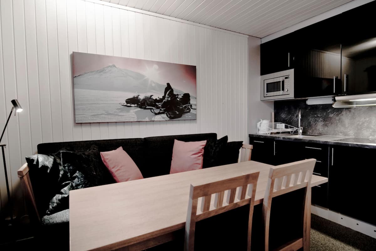 A modern kitchen with a microwave, black cabinets, and a wooden dining table.