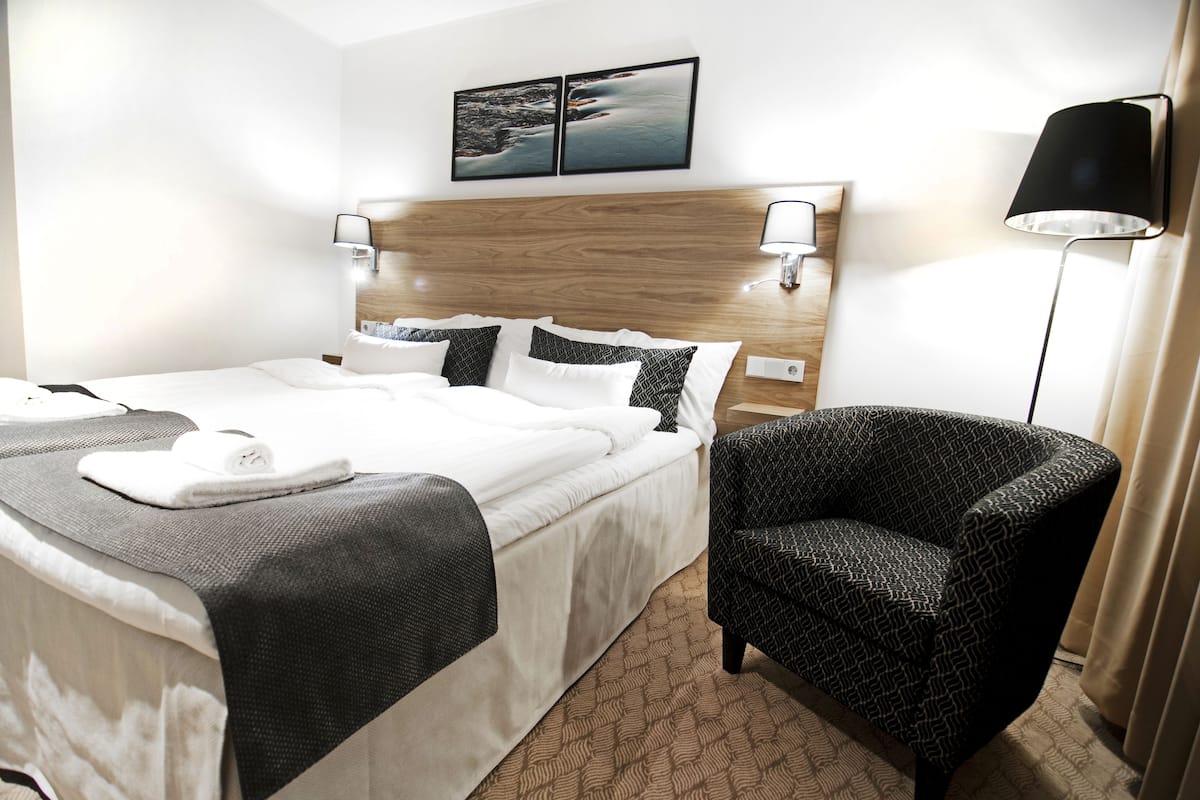 A hotel room with a large bed, two bedside tables, a chair, and a nightstand.