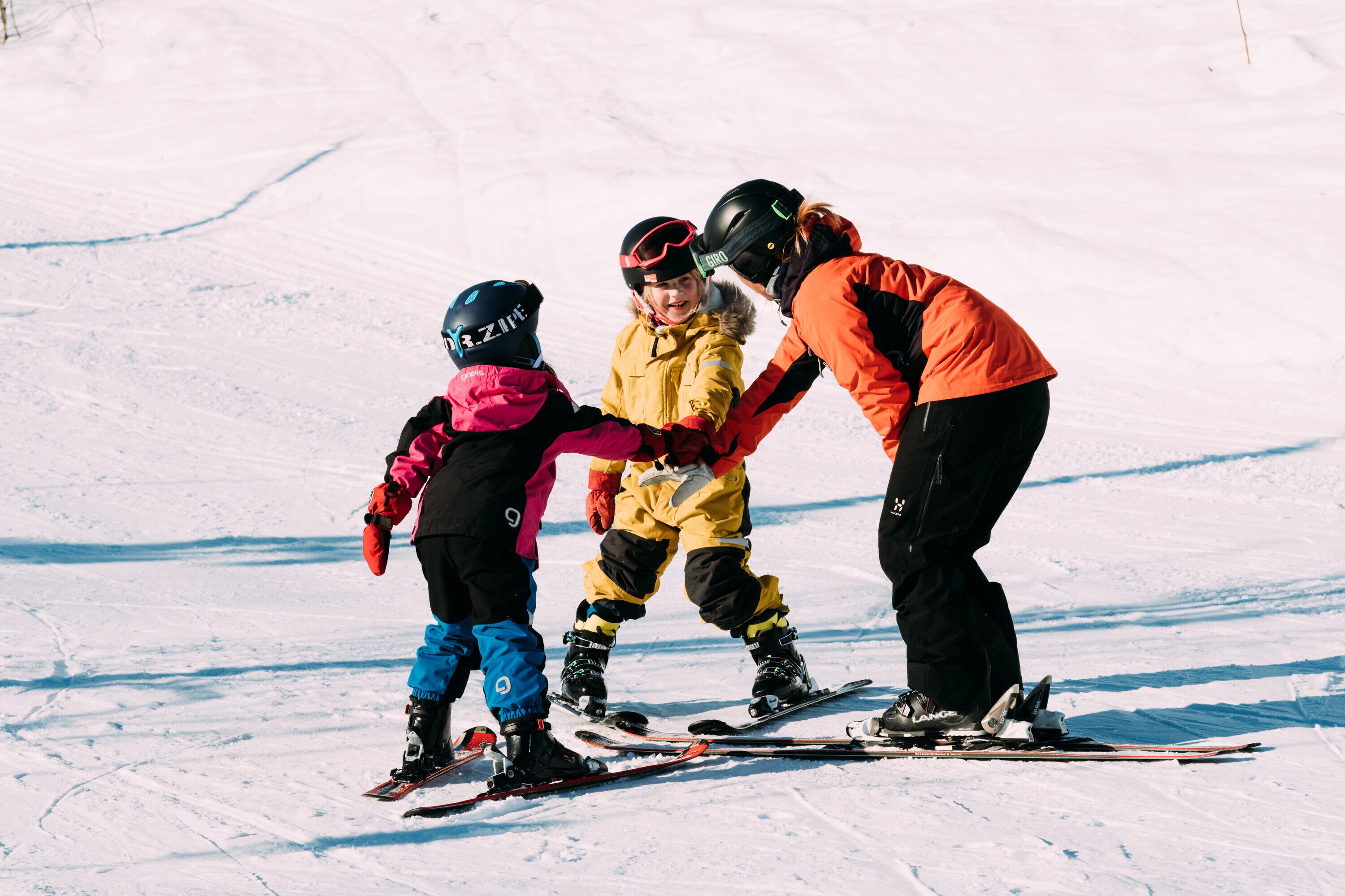 Une piste de ski enneigée où l’on voit trois personnes portant des vêtements de ski.