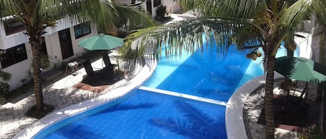 Una piscina al aire libre, sombrillas, tumbonas