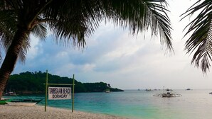 Ein Strand mit einem Schild, auf dem 'TAMBISAN BEACH BORACAY' steht.