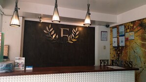 Ein Empfangsschalter mit dunkler Holzoptik, einem großen 'F'-Monogramm und drei Pendelleuchten.