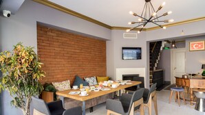 A modern dining area with a brick wall, a dining table set for breakfast, and a staircase leading to an upper level. - Sublime Porte Hotel (Istanbul)