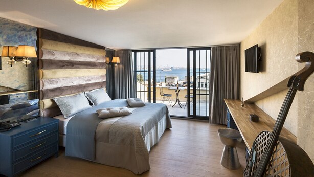 A spacious bedroom with a large bed, a desk, and a view of the sea. - Sublime Porte Hotel (Istanbul)