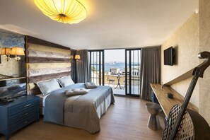 Um quarto espaçoso com uma cama grande, uma escrivaninha e vista para o mar.