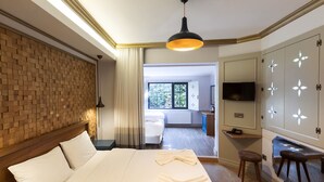A hotel room with a large bed, a wooden headboard, a TV, a wardrobe with decorative panels, and a view of the adjacent room. - Sublime Porte Hotel (Istanbul)