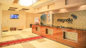 A hotel reception area with a modern design, including a reception desk, seating area, and a television screen. - Magnolia Addis Hotel (Addis Ababa)
