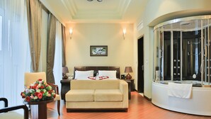 A hotel room with a bed, a sofa, a shower area, and a chandelier. - Magnolia Addis Hotel (Addis Ababa)
