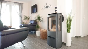 A modern living room with a sofa, a fireplace, and potted plants.