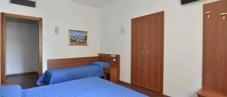 A hotel room with two beds, a wardrobe, a television, and a painting on the wall.