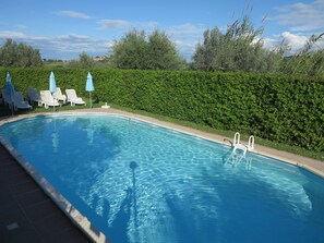 Una piscina al aire libre de temporada, sombrillas