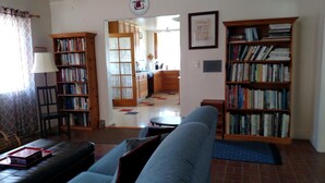 Una sala de estar con un sofá, una estantería y un comedor con mesa y sillas.