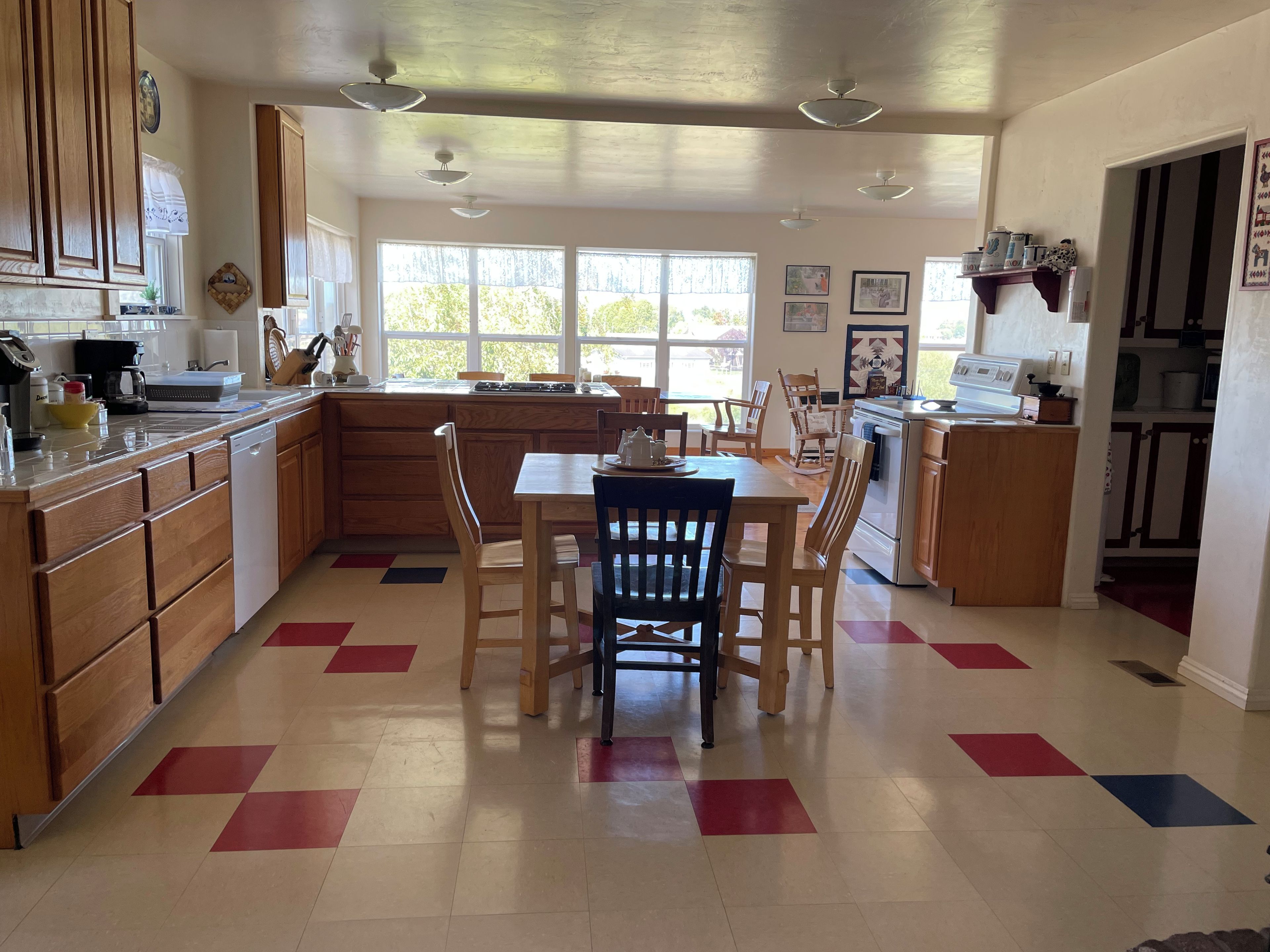 A kitchen with wooden cabinets, a dining table with chairs, and a large window providing natural light.