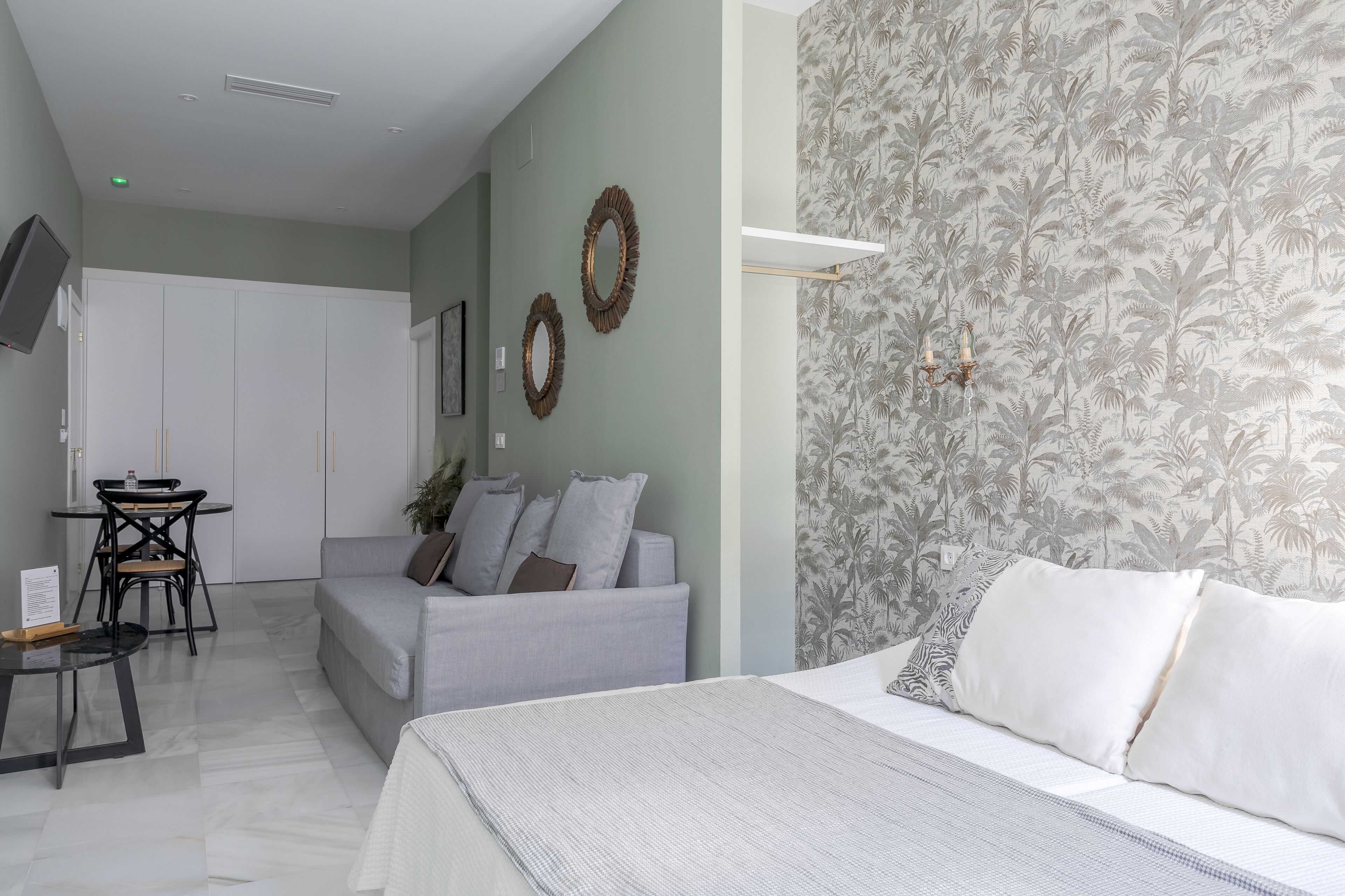 Un dormitorio con cama, sofá, escritorio y televisor.