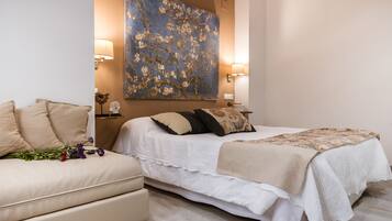 A bedroom with a bed, a sofa, and a large floral painting on the wall.