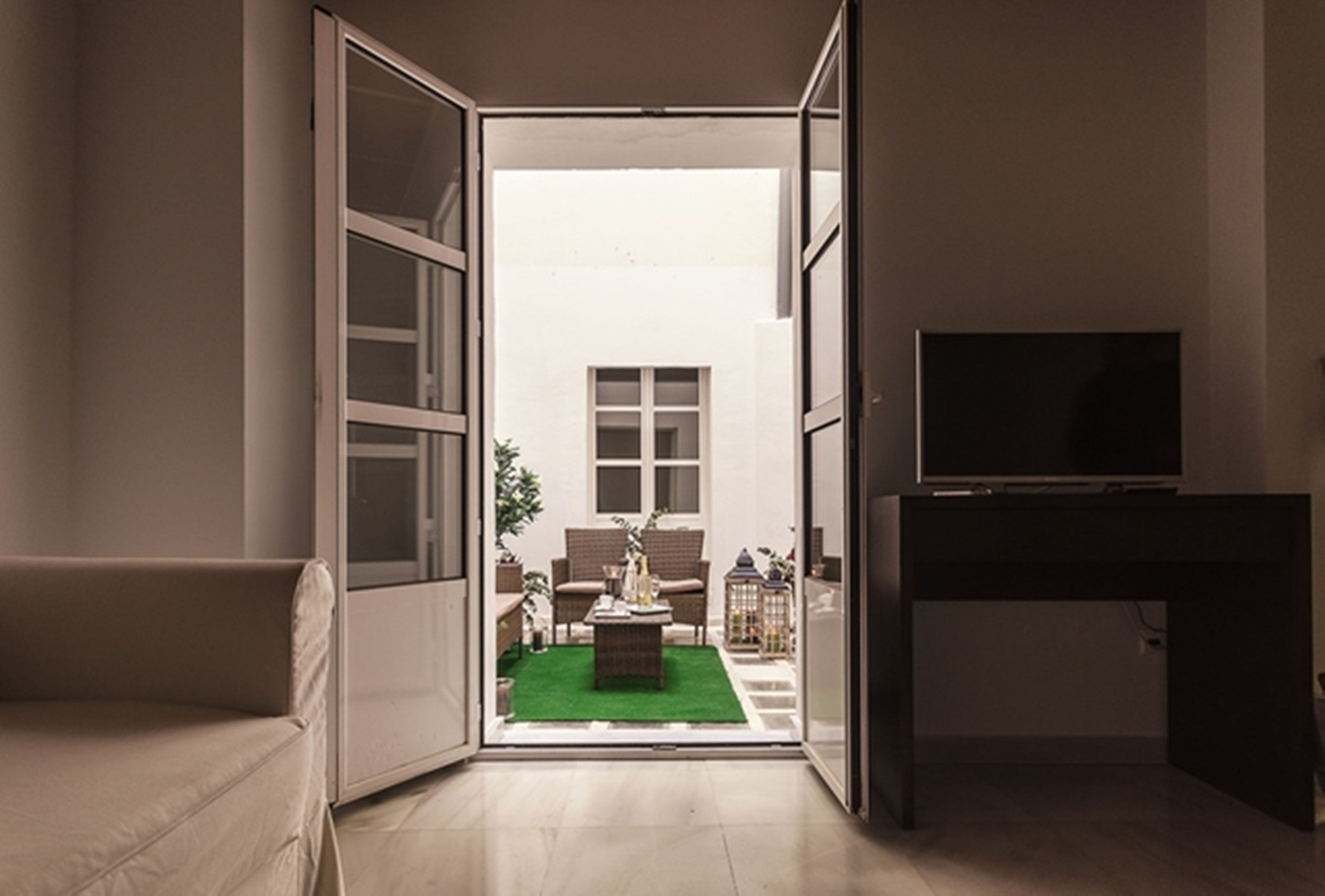 Een moderne woonkamer met een bank, een salontafel en een tv op een standaard.