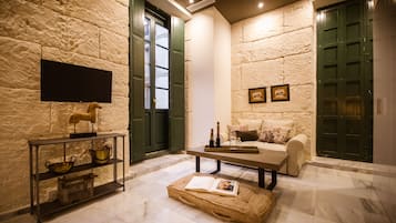 Estudio Deluxe, baño privado | Área de sala de estar | Televisión de pantalla plana de 32 pulgadas con canales vía satélite