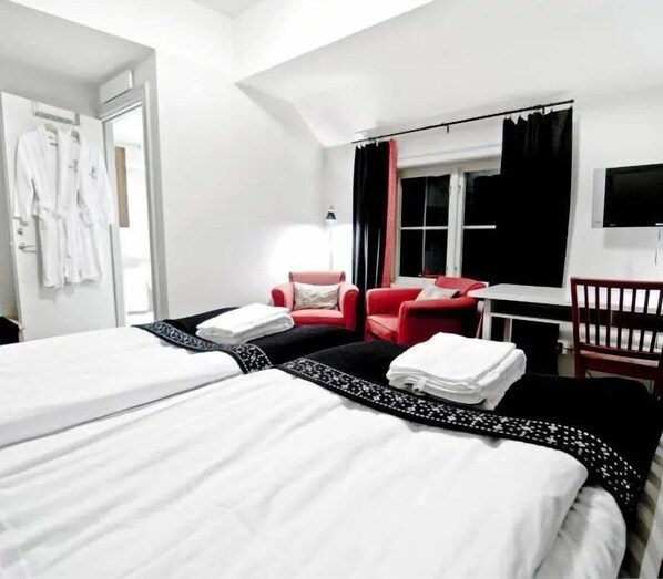 Une chambre d’hôtel avec deux lits, un canapé rouge, un bureau et une télévision.