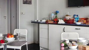 A compact kitchen with white cabinets, a microwave, and a dining area with a table set for two. - B&B Binario Uno (Taranto)