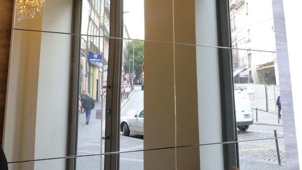 A hotel lobby with a large glass door, a chandelier, and a view of the street outside. - Letheshome Apartments (Porto)