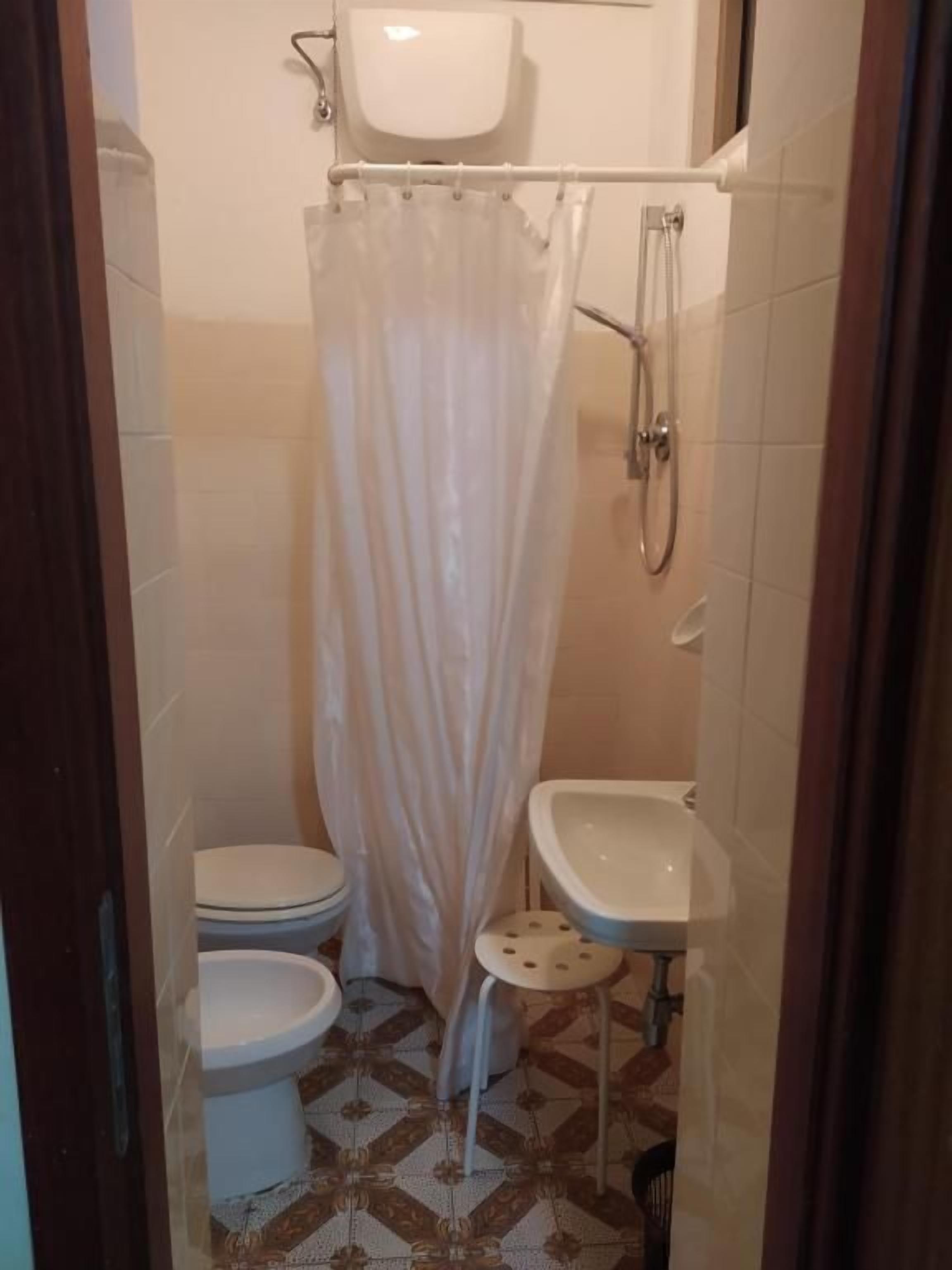A small bathroom with a shower, toilet, and sink.