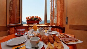 A breakfast table with plates, cups, and food items. - Amelia Hotel (Marliana)