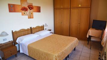 Ein Schlafzimmer mit Bett, Holzschrank, Nachttisch, Lampe und Fernseher.