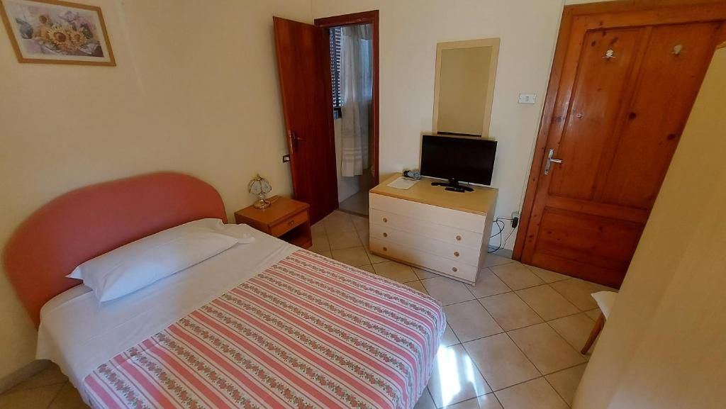 Ein Schlafzimmer mit Bett, Kommode, Fernseher und einer Tür.
