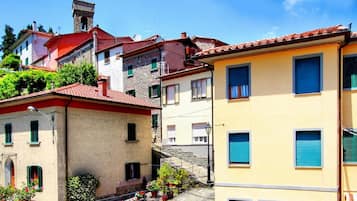 A residential area with buildings featuring red-tiled roofs, a stone tower, and a staircase leading to a higher level.