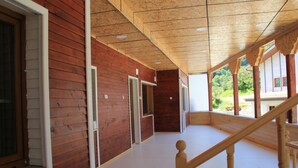 Un couloir en bois, à ciel ouvert, avec un escalier menant à un niveau supérieur.