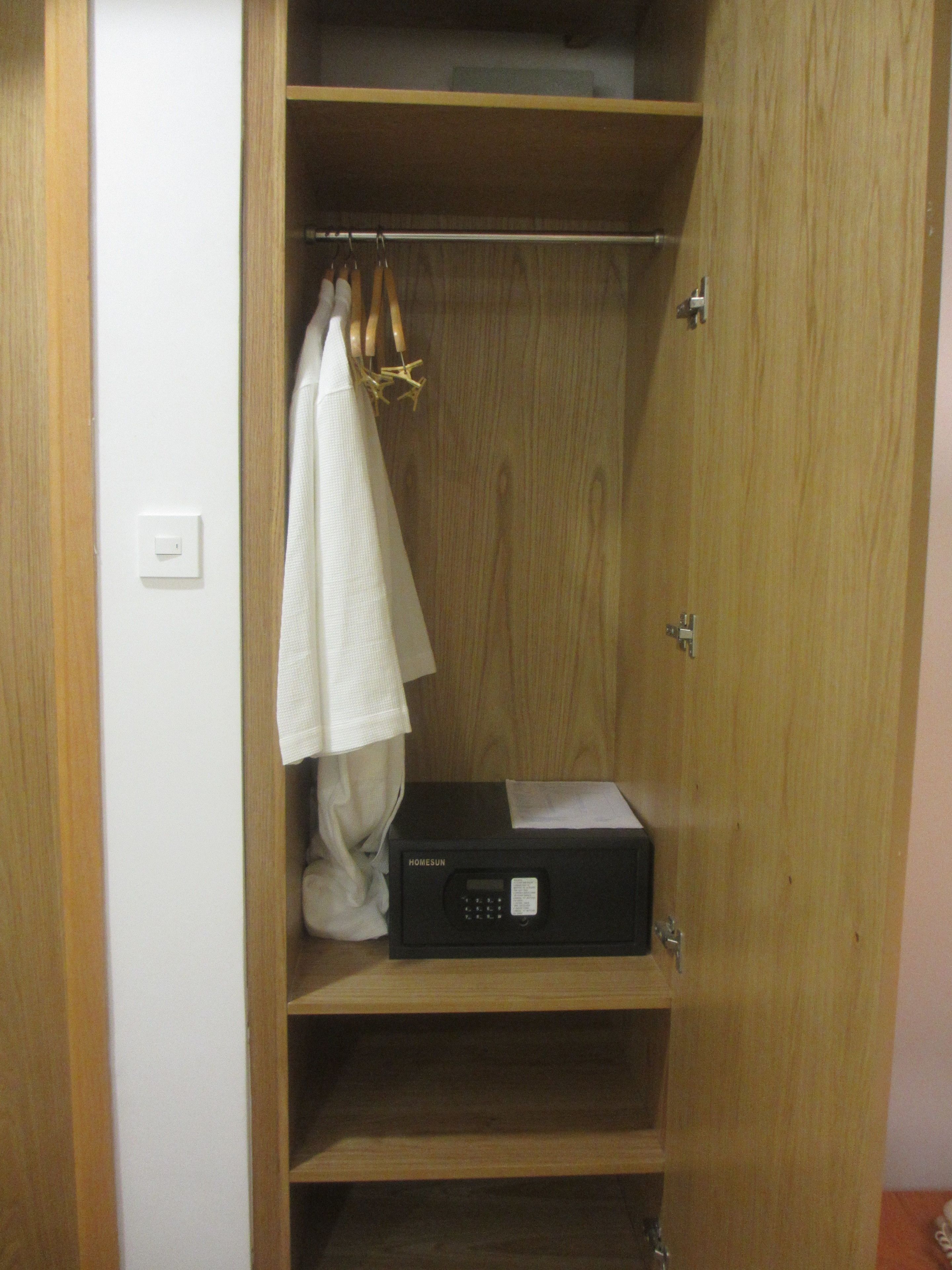 A wooden wardrobe with a microwave on the bottom shelf.