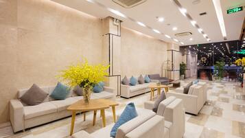 A modern lobby with sofas, a coffee table, and a vase with yellow flowers.