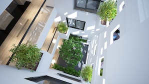 A modern interior with white walls, geometric patterns, and multiple potted plants. - Ale Nhatrang Hotel (Nha Trang)