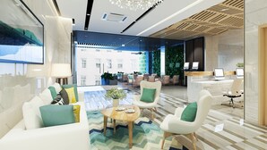 Un moderno hall de hotel con un área de descanso, una recepción y vistas al exterior.