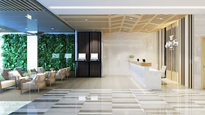 A modern reception area with a reception desk, seating area with chairs, a green wall with plants, and a check-in counter. - Ale Nhatrang Hotel (Nha Trang)