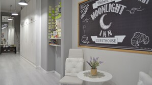 A modern hotel corridor with a chalkboard sign reading "Welcome to Moonlight Inn Guesthouse" and a clock above it. - Moonlight Inn Guest House (Rome)