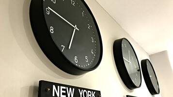 Three clocks on a wall, each with a label below indicating different cities: New York, Paris, and Tokyo.
