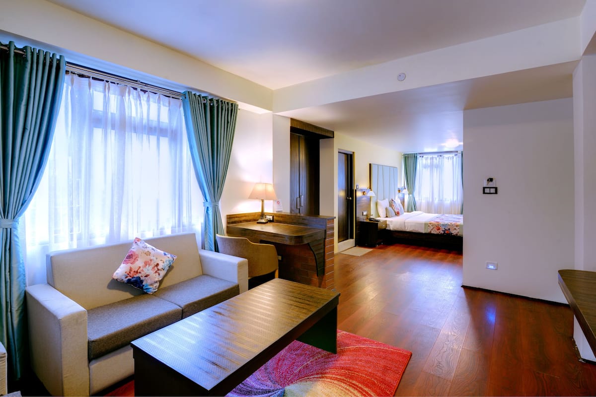 Habitació d'hotel amb un sofà, una taula de centre de fusta, escriptori i llit.