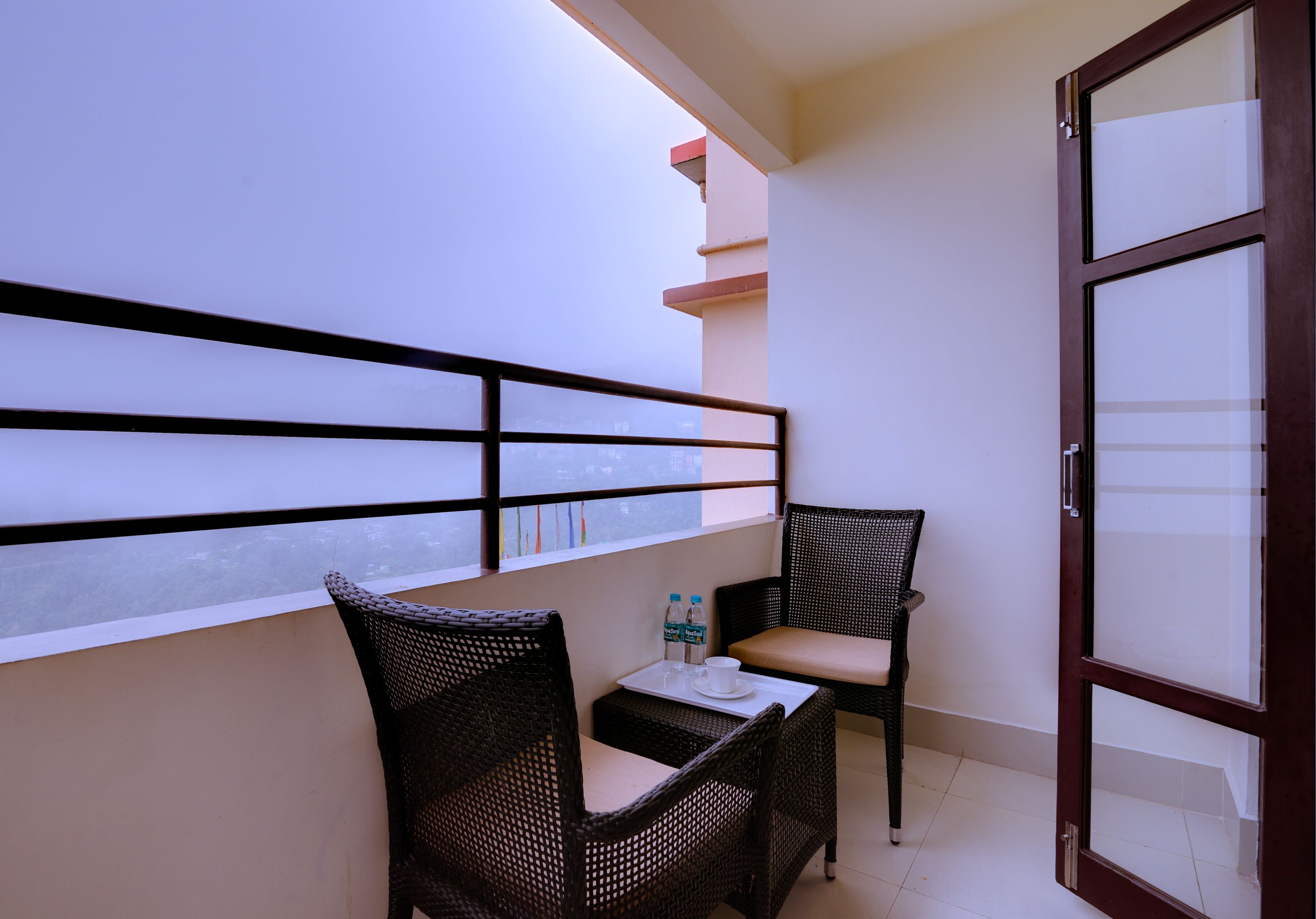 A balcony with wicker chairs, a small table, and a bottle of water.