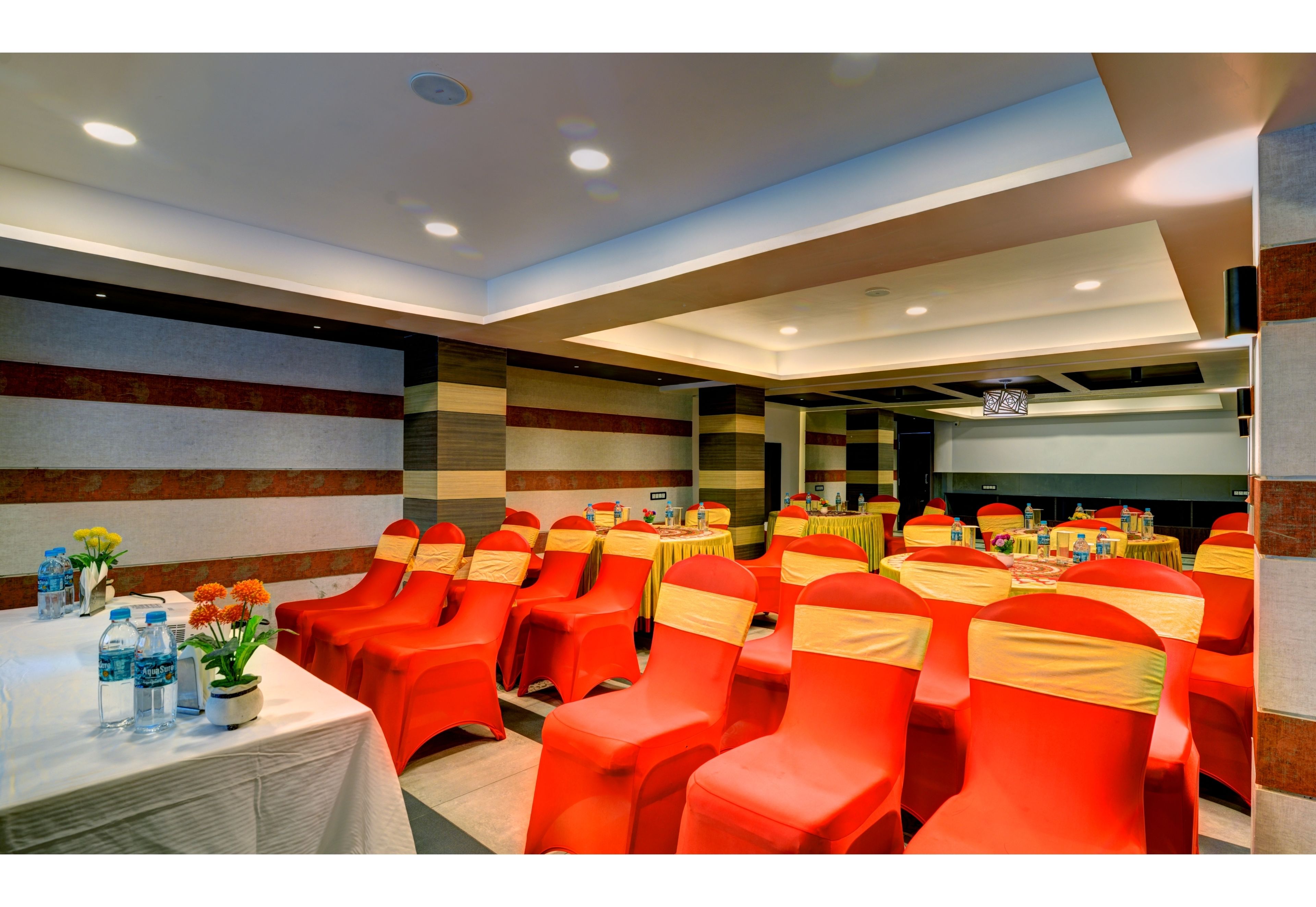 A conference room with rows of red chairs, tables with yellow sashes, and a stage area.