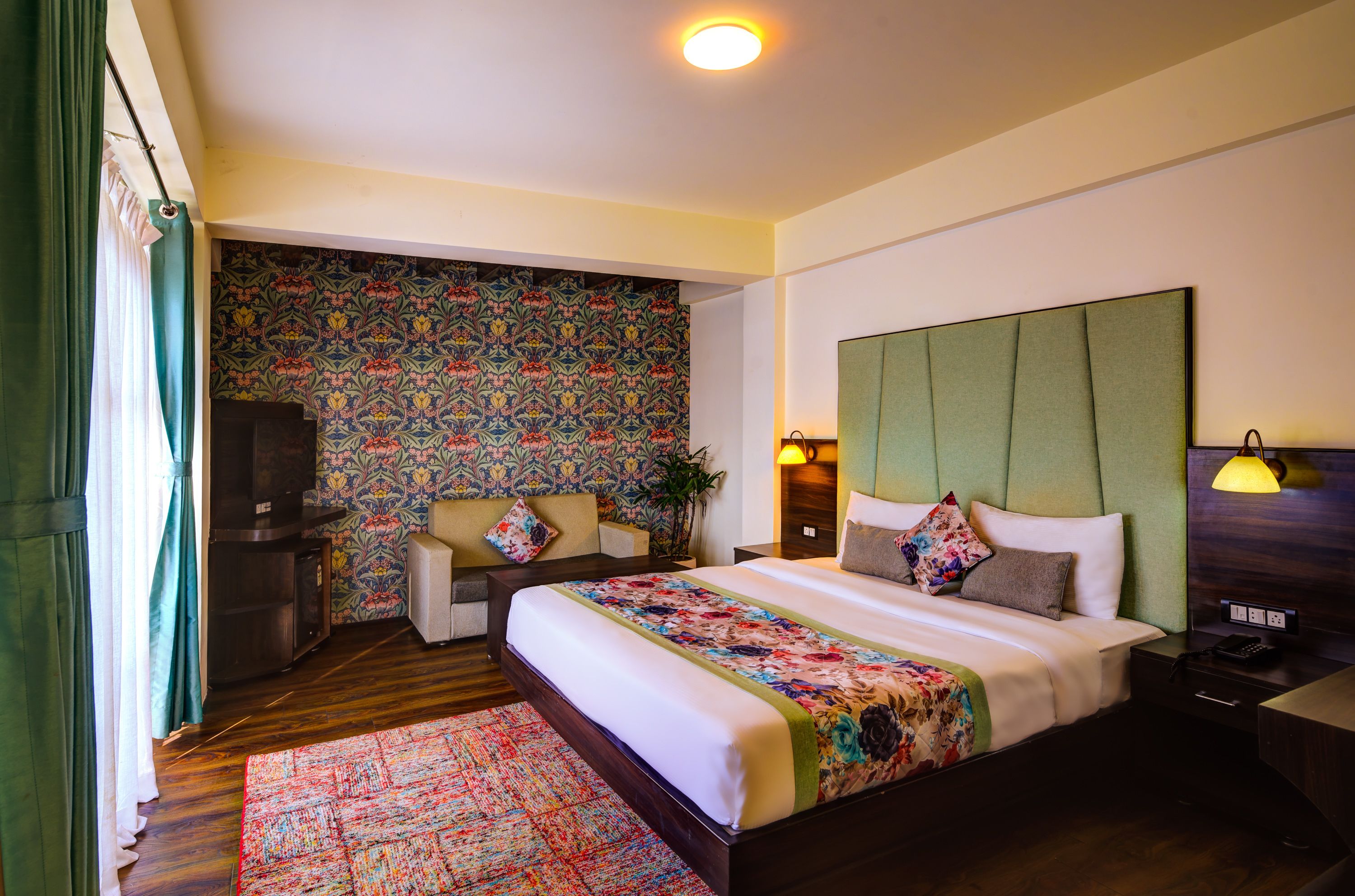 Una habitación de hotel con una cama grande, televisión, sofá y un papel tapiz estampado.