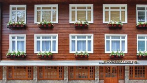 Fachada de hotel con múltiples ventanas, algunas con jardineras, y un letrero que dice 