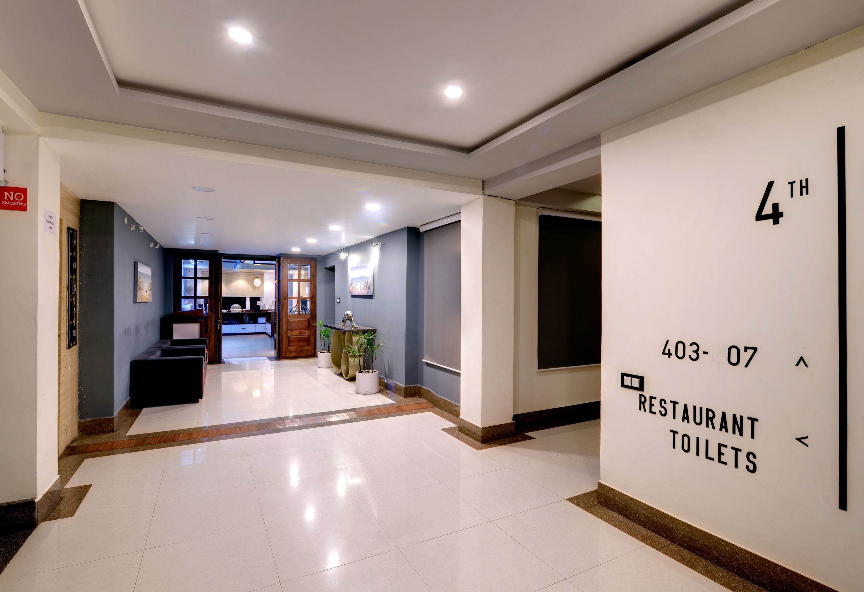A hotel lobby with a clear sign indicating the 4th floor and the location of restaurant and toilet facilities.