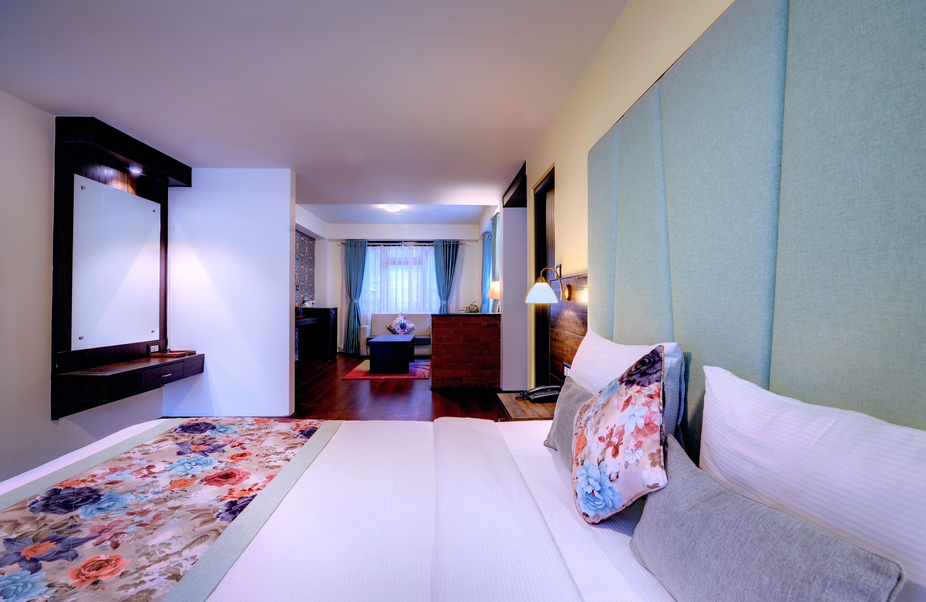 Una habitación de hotel con una cama grande, un escritorio, una silla, una mesita y un espejo.