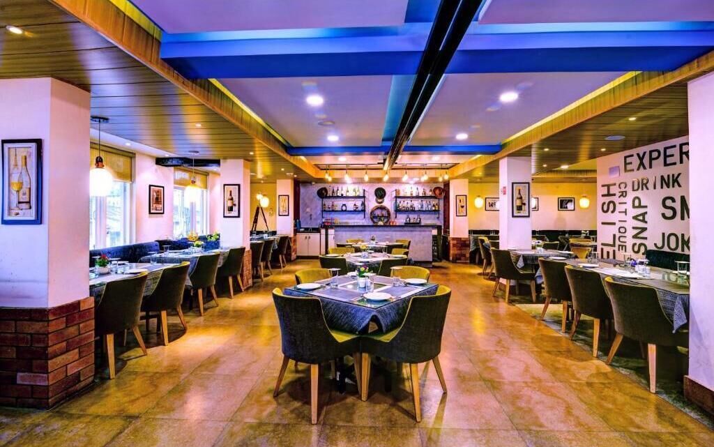 Ein Restaurant mit mehreren Tischen und Stühlen, einer Bar und gerahmten Bildern an den Wänden.