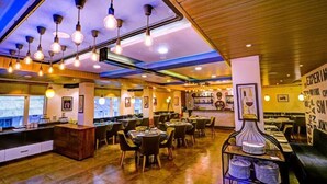 Un restaurante con varias mesas, lámparas colgantes y una zona de bar.
