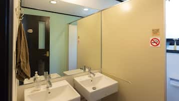 A bathroom with two sinks, a towel rack, and a mirror. There is a sign indicating no food disposal and no smoking.