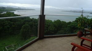 A balcony with a view of a river and greenery. - Cliffside View Hotel (Meyungs)